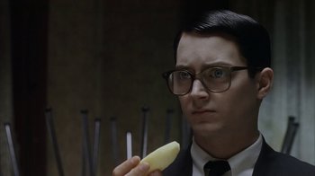 Movie still from “Everything Is Illuminated” (2005), directed by Liev Schreiber – A man in a suit and tie holding a piece of banana; Close Up shot, Over the shoulder angle