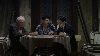 Movie still from “Everything Is Illuminated” (2005), directed by Liev Schreiber – A group of people sitting at a table with drinks; Medium shot, Over the shoulder angle