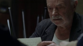 Movie still from “Everything Is Illuminated” (2005), directed by Liev Schreiber – An older man sitting at a table looking at a piece of paper; Close Up shot, Over the shoulder angle