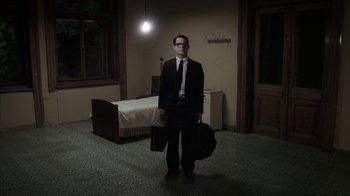 Movie still from “Everything Is Illuminated” (2005), directed by Liev Schreiber – A man in a suit and tie holding a suitcase; Wide shot, High angle