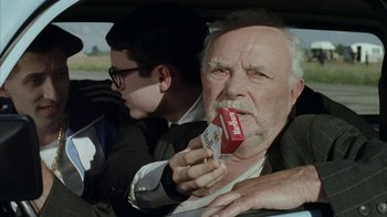 Movie still from “Everything Is Illuminated” (2005), directed by Liev Schreiber – An older man holding a box of cigarettes in a car; Close Up shot, Over the shoulder angle