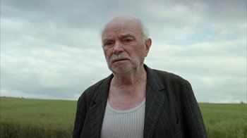 Movie still from “Everything Is Illuminated” (2005), directed by Liev Schreiber – An old man with a beard and a jacket on; Close Up shot, Low angle