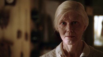 Movie still from “Everything Is Illuminated” (2005), directed by Liev Schreiber – An older woman with a white hair and a white shirt; Close Up shot, Low angle