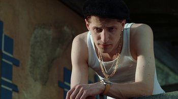 Movie still from “Everything Is Illuminated” (2005), directed by Liev Schreiber – A young man wearing a hat and a chain around his neck looking down; Close Up shot, Low angle