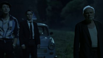 Movie still from “Everything Is Illuminated” (2005), directed by Liev Schreiber – Two men standing in front of an old car in the dark; Medium shot, Over the shoulder angle