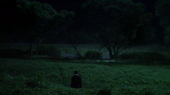 Movie still from “Everything Is Illuminated” (2005), directed by Liev Schreiber – A man in a black suit sitting in a field at night; Extreme Wide shot, High angle