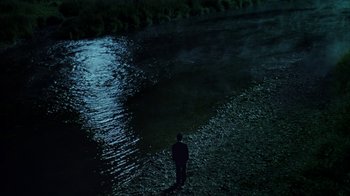 Movie still from “Everything Is Illuminated” (2005), directed by Liev Schreiber – A man standing in the middle of a river at night; Extreme Wide shot, High angle