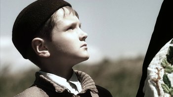 Movie still from “Everything Is Illuminated” (2005), directed by Liev Schreiber – A young boy wearing a hat looking up at the sky; Close Up shot, Low angle
