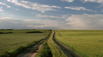 Movie still from “Everything Is Illuminated” (2005), directed by Liev Schreiber – A car driving down a dirt road through a field; Extreme Wide shot, High angle