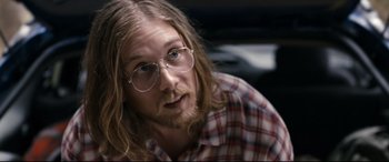 Movie still from “Evil Dead” (2013), directed by Fede Alvarez – A man with long hair wearing glasses and a plaid shirt; Close Up shot, Over the shoulder angle