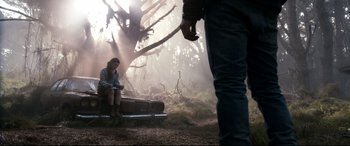 Movie still from “Evil Dead” (2013), directed by Fede Alvarez – A woman sitting on top of a trunk in the woods; Wide shot, Low angle