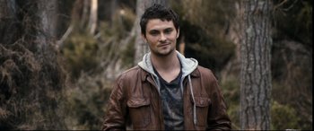 Movie still from “Evil Dead” (2013), directed by Fede Alvarez – A man wearing a brown jacket standing next to a tree; Close Up shot, Over the shoulder angle