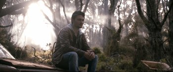 Movie still from “Evil Dead” (2013), directed by Fede Alvarez – A man sitting on the ground in the woods; Medium shot, Low angle