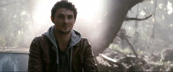 Movie still from “Evil Dead” (2013), directed by Fede Alvarez – A man in a brown leather jacket is smiling for the camera; Close Up shot, Over the shoulder angle