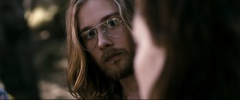 Movie still from “Evil Dead” (2013), directed by Fede Alvarez – A person with long hair wearing glasses; Close Up shot, Over the shoulder angle