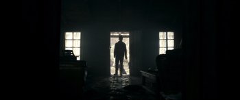 Movie still from “Evil Dead” (2013), directed by Fede Alvarez – A man standing in a doorway in the dark; Wide shot, Low angle