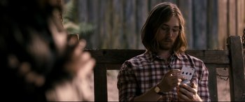 Movie still from “Evil Dead” (2013), directed by Fede Alvarez – A man sitting on top of a wooden park bench; Medium shot, Over the shoulder angle