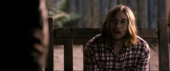 Movie still from “Evil Dead” (2013), directed by Fede Alvarez – A man sitting on a wooden bench wearing glasses; Medium shot, Over the shoulder angle