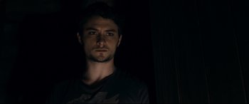 Movie still from “Evil Dead” (2013), directed by Fede Alvarez – A man in a black shirt is in the dark; Close Up shot, Low angle
