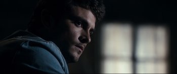 Movie still from “Evil Dead” (2013), directed by Fede Alvarez – A man's face in a dark room; Close Up shot, Over the shoulder angle