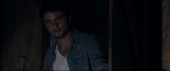 Movie still from “Evil Dead” (2013), directed by Fede Alvarez – A man in a denim shirt is standing in a dark room; Close Up shot, Over the shoulder angle