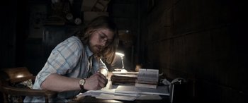 Movie still from “Evil Dead” (2013), directed by Fede Alvarez – A man sitting at a table looking at a book; Medium shot, Over the shoulder angle