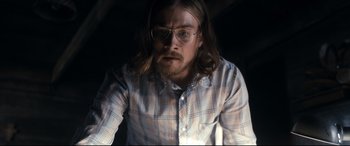 Movie still from “Evil Dead” (2013), directed by Fede Alvarez – A man with long hair wearing glasses and a plaid shirt; Medium shot, Low angle