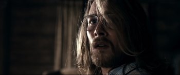 Movie still from “Evil Dead” (2013), directed by Fede Alvarez – A person with long hair wearing glasses; Close Up shot, Over the shoulder angle