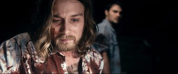 Movie still from “Evil Dead” (2013), directed by Fede Alvarez – A man with long hair and a bloody shirt on; Close Up shot, Over the shoulder angle