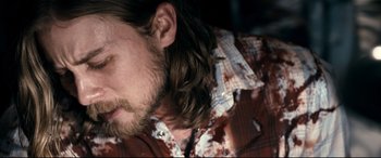 Movie still from “Evil Dead” (2013), directed by Fede Alvarez – A person with long hair and a beard; Close Up shot, Over the shoulder angle