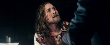 Movie still from “Evil Dead” (2013), directed by Fede Alvarez – A person wearing a shirt with blood all over his face; Close Up shot, Over the shoulder angle