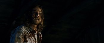 Movie still from “Evil Dead” (2013), directed by Fede Alvarez – A man with long brown hair and a brown shirt; Close Up shot, Low angle