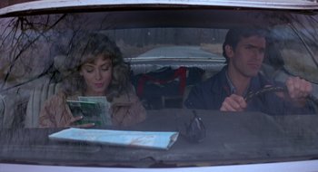 Movie still from “Evil Dead II” (1987), directed by Sam Raimi – A man and a woman sitting in the back of a car; Medium shot, High angle