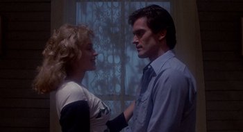 Movie still from “Evil Dead II” (1987), directed by Sam Raimi – A man and a woman standing next to each other in front of a window; Medium shot, Low angle
