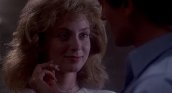 Movie still from “Evil Dead II” (1987), directed by Sam Raimi – A woman is smiling while a man is holding her ear; Close Up shot, Over the shoulder angle