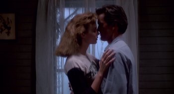 Movie still from “Evil Dead II” (1987), directed by Sam Raimi – A man and a woman kissing in front of a window; Medium shot, Low angle