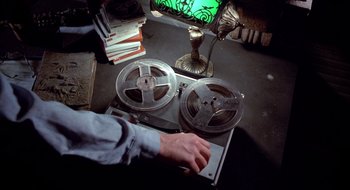 Movie still from “Evil Dead II” (1987), directed by Sam Raimi – A person is holding a pair of tape cassettes; Close Up shot, Overhead angle