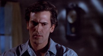 Movie still from “Evil Dead II” (1987), directed by Sam Raimi – A man that is looking at the camera; Close Up shot, Over the shoulder angle