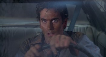 Movie still from “Evil Dead II” (1987), directed by Sam Raimi – A person holding a steering wheel; Close Up shot, Over the shoulder angle