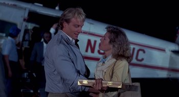 Movie still from “Evil Dead II” (1987), directed by Sam Raimi – A man and a woman standing next to each other in front of an airplane; Medium shot, Low angle