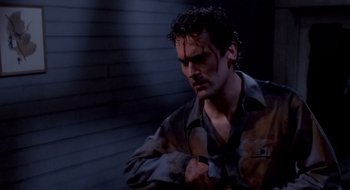 Movie still from “Evil Dead II” (1987), directed by Sam Raimi – A person wearing a shirt with blood all over his face; Medium shot, Low angle