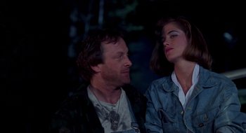 Movie still from “Evil Dead II” (1987), directed by Sam Raimi – A man and a woman sitting next to each other in the dark; Medium shot, Low angle