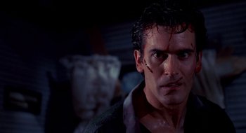 Movie still from “Evil Dead II” (1987), directed by Sam Raimi – A person wearing a shirt with blood all over his face; Close Up shot, Low angle