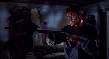 Movie still from “Evil Dead II” (1987), directed by Sam Raimi – A man holding a gun with blood on his face; Medium shot, Low angle