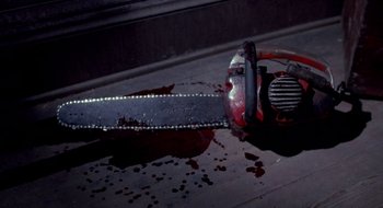 Movie still from “Evil Dead II” (1987), directed by Sam Raimi – A red chain saw sitting on top of a wooden floor; Extreme Close Up shot, High angle