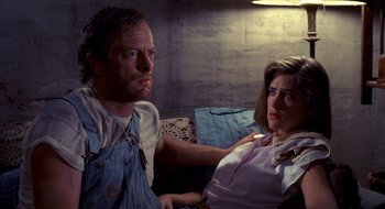 Movie still from “Evil Dead II” (1987), directed by Sam Raimi – A man and a woman sitting next to each other on a couch; Medium shot, Low angle