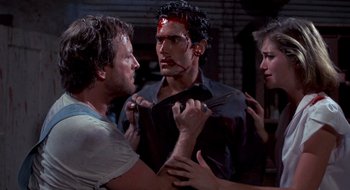 Movie still from “Evil Dead II” (1987), directed by Sam Raimi – A group of people standing next to each other; Medium shot, Over the shoulder angle