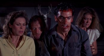 Movie still from “Evil Dead II” (1987), directed by Sam Raimi – A group of people standing next to each other with blood on their faces; Medium shot, Over the shoulder angle