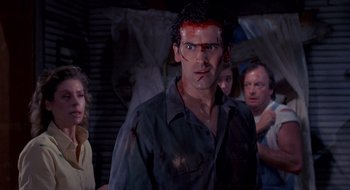 Movie still from “Evil Dead II” (1987), directed by Sam Raimi – A group of people standing in a room; Medium shot, Over the shoulder angle