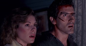 Movie still from “Evil Dead II” (1987), directed by Sam Raimi – A man and a woman looking at the camera; Close Up shot, Low angle